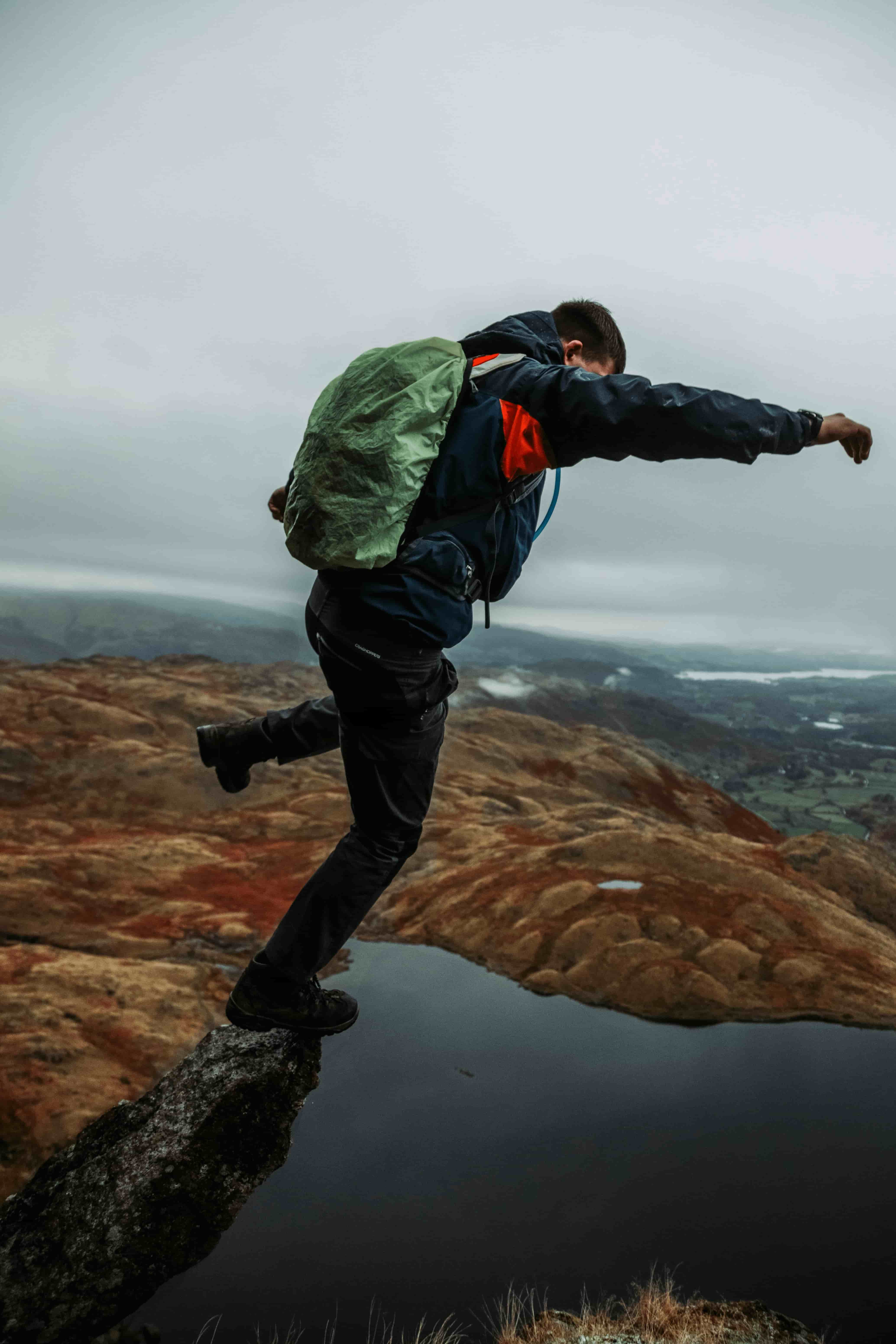 The upper body of a man jumping over a river in rainproof clothing
